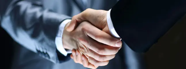 Two men in a suit shake hands.